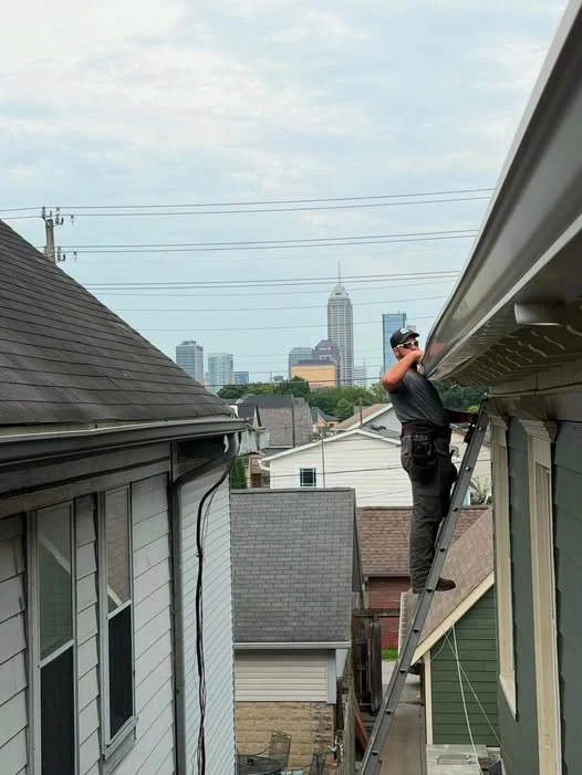 Alex working on an Indianapolis roofline with the downtown skyline visible behind him