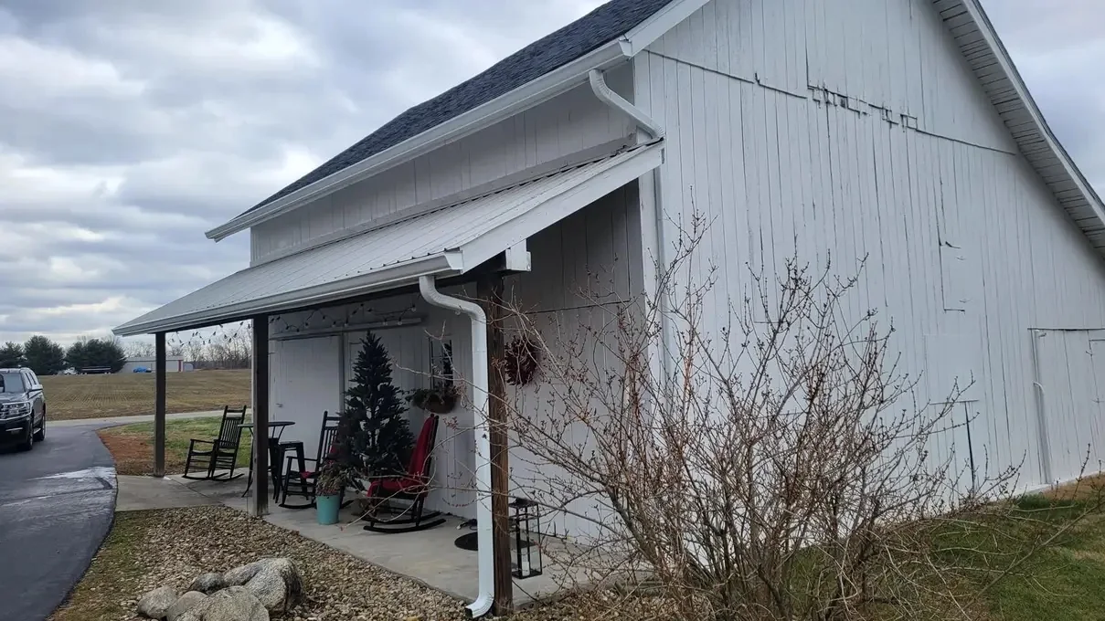 White building with completed gutter and downspout along a porch roofline