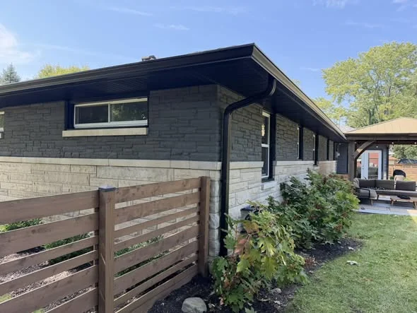 Corner view showing matching black gutter and downspout routing