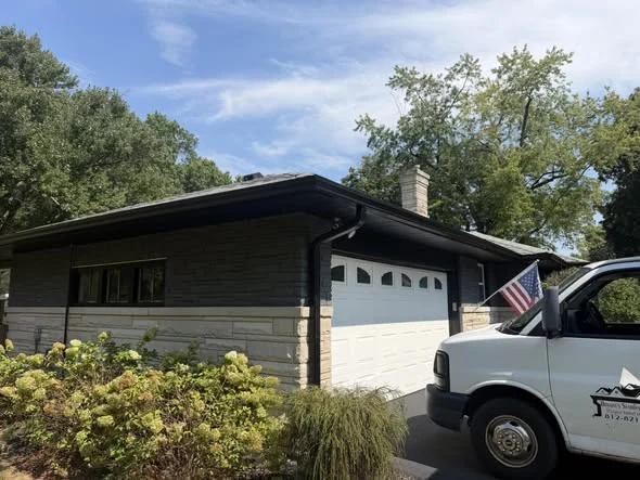 Garage-side black gutter installation with Bryant's work truck